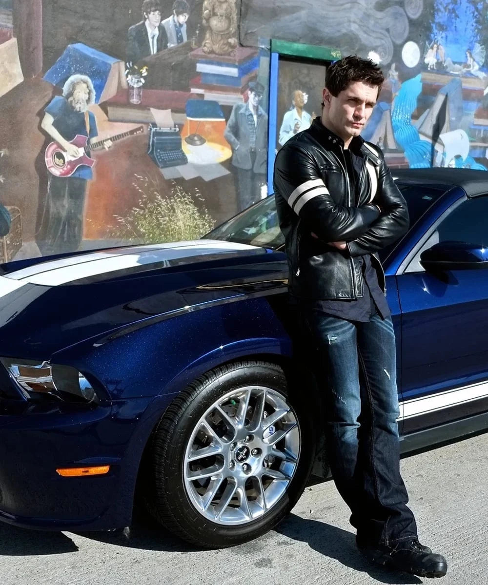 Actor Sam Witwer wearing Soul Revolverâ€™s black Driver San Francisco John Tanner replica leather jacket beside a blue muscle car