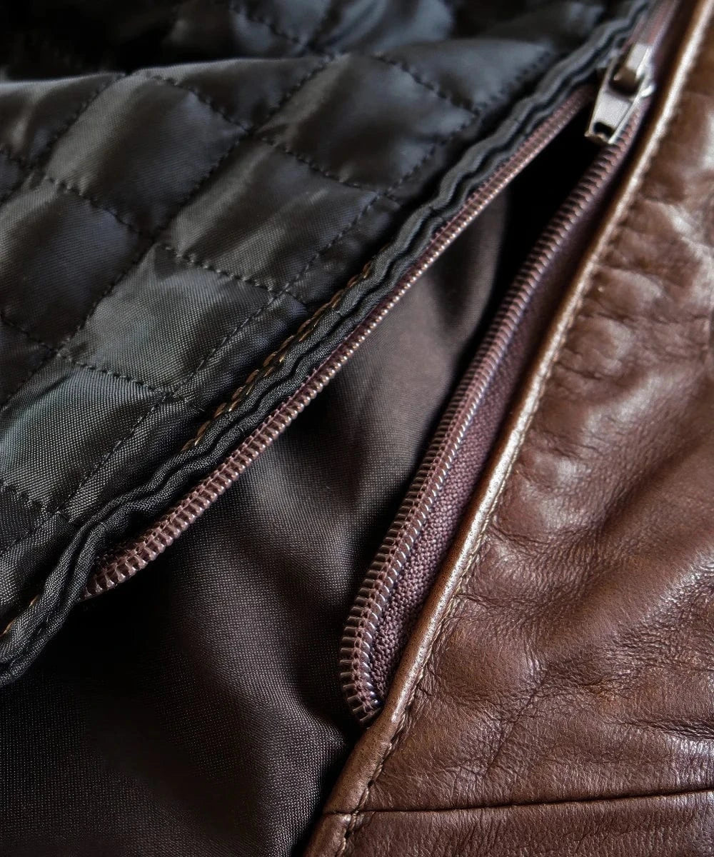 Close-up view of quilted lining and inner zipper detail inside slim fit brown leather jacket